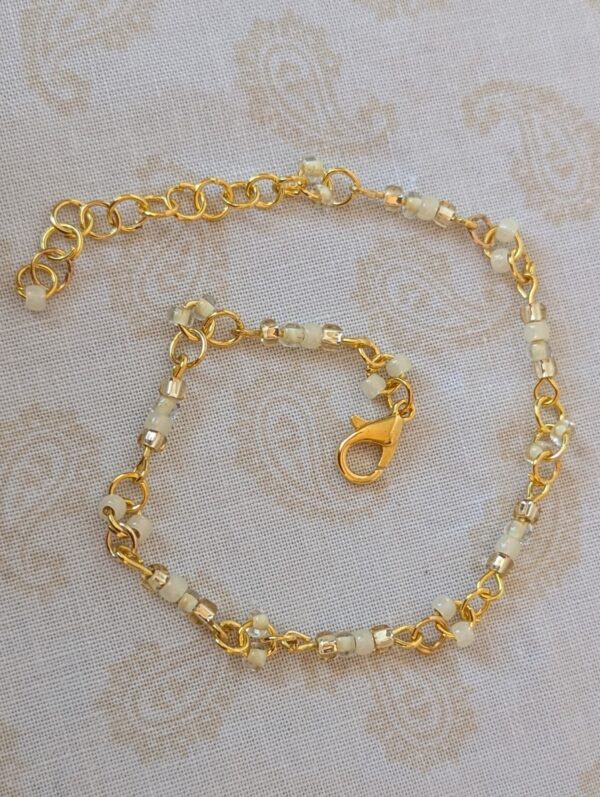 Gold-toned beaded chain bracelet with creamy ivory, champagne, and pale gold glass seed beads and lobster clasp